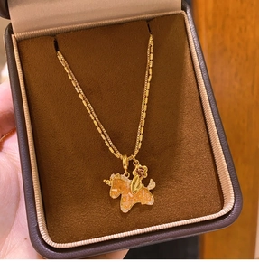 Macro shot of gold unicorn necklace with orange gemstone in a brown velvet jewelry box