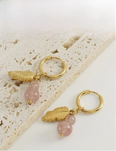 Close-up of golden leaf and pink natural stone beads on a stainless steel hoop earring
