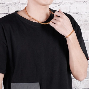 Close-up of gold stainless steel woven chain necklace and bracelet set on a male model