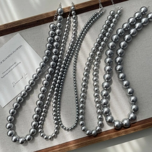 Elegant grey pearl necklaces in various sizes on white linen cloth for a French retro look