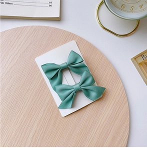 Detailed view of mint green satin bow hair clips on a wooden tray for girls