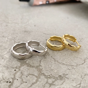 Close-up of geometric quilted texture and S925 hallmarks on silver and gold earrings