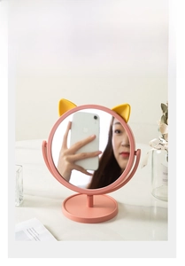 Detail of pink cat-ear vanity mirror with yellow ears and high-definition rotating mirror