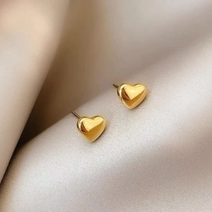 Detailed macro view of gold heart stud earrings on elegant silk fabric background