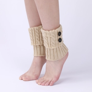 Detail of beige cable knit leg warmers with black buttons and ribbed texture finish