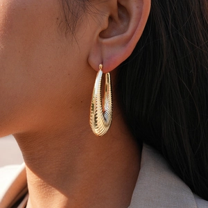Detail shot of golden ribbed water-drop earrings with polished textured finish
