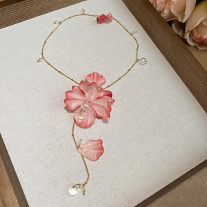Close-up of a pink petal pendant necklace with sparkling crystal beads on a gold chain