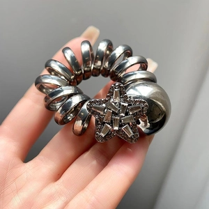 Detail of silver spiral hair tie featuring a rhinestone star and metal bead charm