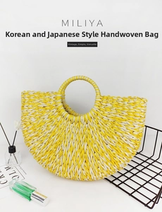 Detail of handmade woven straw tote bag with semi-circular shape and circular top handle