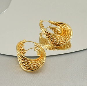 Macro detail of gold-plated braided hoop earrings with multi-layered twisted texture