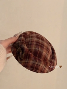 Gedetailleerde opname van een bruine geruite baret met fluwelen strik en wollen textuur