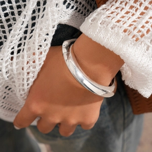 Close-up of a chunky silver resin bangle on a wrist with white crochet and denim