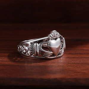 Détail macro d'une bague Claddagh argentée avec mains tenant un cœur et couronne