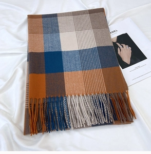 Detailed close-up of thick plaid scarf with orange and blue checks and tassel fringe