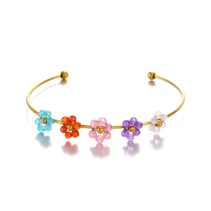 Golden stainless steel cuff bracelet with five colorful woven crystal flowers on white background