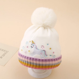 Détail d'un bonnet en tricot licorne blanc avec un gros pompon et des rayures colorées