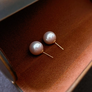 Macro shot of elegant round pink-brown pearl stud earrings with golden finish