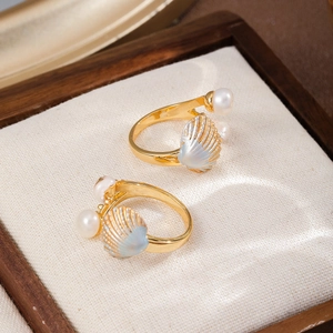 Detailed macro view of golden shell texture ring with round pearl on white fabric