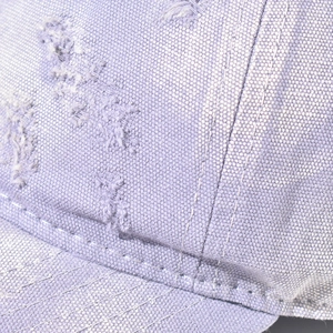 Macro shot of distressed lavender cotton baseball cap with vintage frayed hole details
