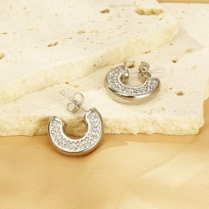 Macro view of silver C-shaped stainless steel earrings with pavé set sparkling crystals