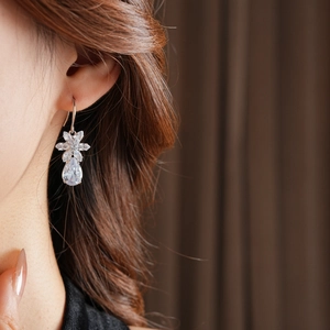 Close-up of elegant silver flower and teardrop zircon drop earrings worn by a model