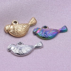 Macro shot of bird-shaped metal pendants in gold, silver, and rainbow on silk