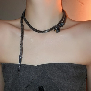 Macro shot of dark grey mesh snake necklace with sparkling rhinestone details and blue crystal eyes