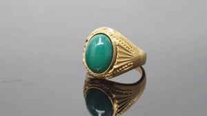 Macro detail of a vintage gold ring featuring a polished oval green stone inlay