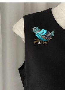 Close-up of vintage blue beaded magpie brooch with crystals on a black suit lapel