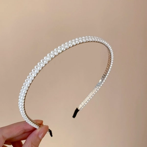 Détail d'un serre-tête en perles à double rangée avec monture fine et embouts noirs