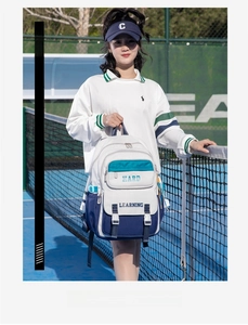 Detail of college style backpack with blue patchwork and Hard Learning print on tennis court