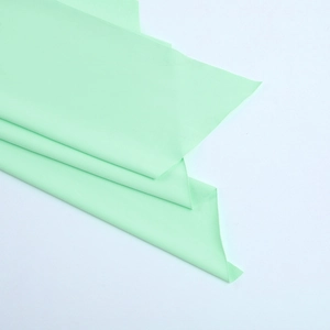 Détail du tissu textile vert menthe clair montrant la texture lisse et les plis