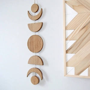 Detailed view of natural wood moon phase wall hanging decor on a white wall
