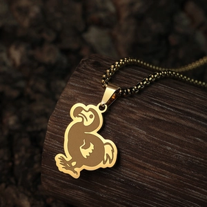 Golden dodo bird pendant necklace with bead chain on wooden trunk, vintage animal jewelry