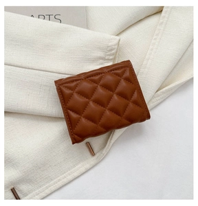 Detail of a brown quilted leather card holder on a textured cream blazer