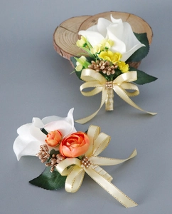 Detail of white calla lily boutonniere with orange accent and champagne ribbon bow