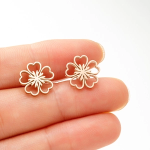 Gros plan de boucles d'oreilles fleurs ajourées or rose avec détails de cœurs