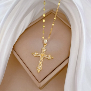 Luxurious gold cross necklace with pave zircons on elegant beige silk jewelry cushion