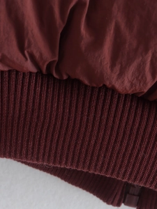 Close-up of burgundy quilted puffer vest showing rib-knitted hem and premium fabric detail