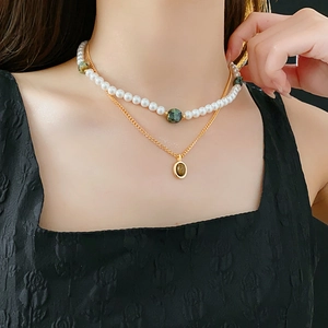 Détail d'un collier double rang avec perles vertes et pendentif ovale doré élégant