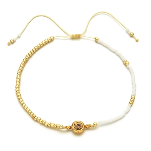 Detail of bohemian beaded bracelet with gold beads, white accents and adjustable cord
