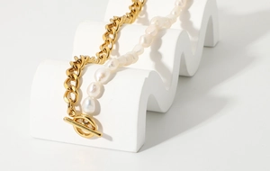 Detailed close-up of a stainless steel Cuban chain and baroque pearl mixed necklace with OT clasp