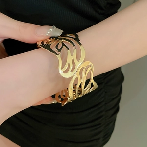 Detail of a golden open-end butterfly cuff bracelet with hollow wings on wrist
