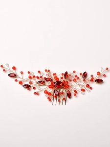 Detailed close-up of handmade bridal hair comb with red crystals and gold wires