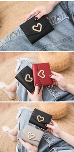 Detailed view of women's tri-fold wallets with heart buckles in black, red, and grey
