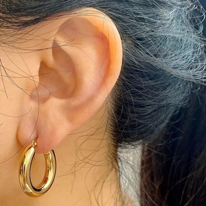 Minimalist thick gold stainless steel hoop earrings shown on model from a side view
