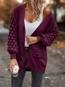 Close-up of deep purple knit cardigan featuring textured puff sleeves and large pockets