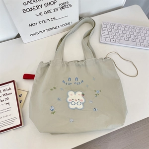 Detailed embroidery of a cute glasses-wearing rabbit and flowers on a beige drawstring tote