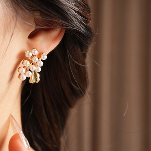 Close-up of vintage gold flower pearl earrings in a grape cluster design on model