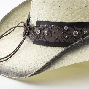 Close-up of cowboy straw hat with rhinestone leather band and rustic metallic studs